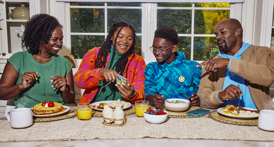 Family of four laughing while eating breakfast